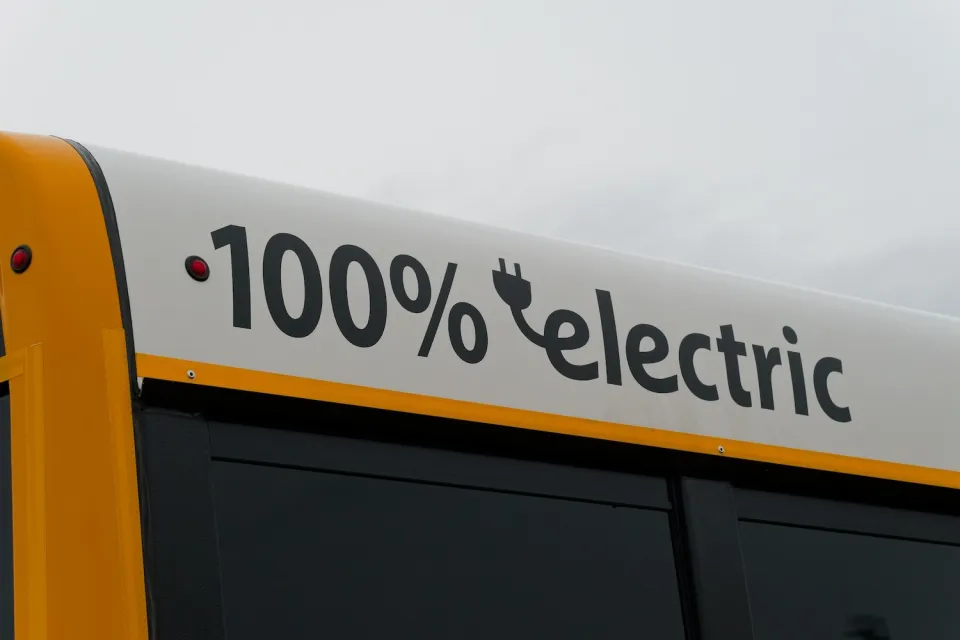 Close-up of white panel at top of school bus with "100% electric" black text.